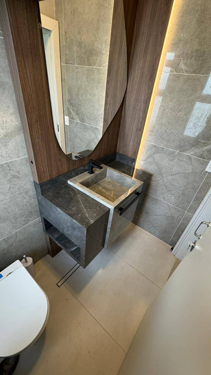 Lavabo com cuba escultórica em porcelanato escuro.